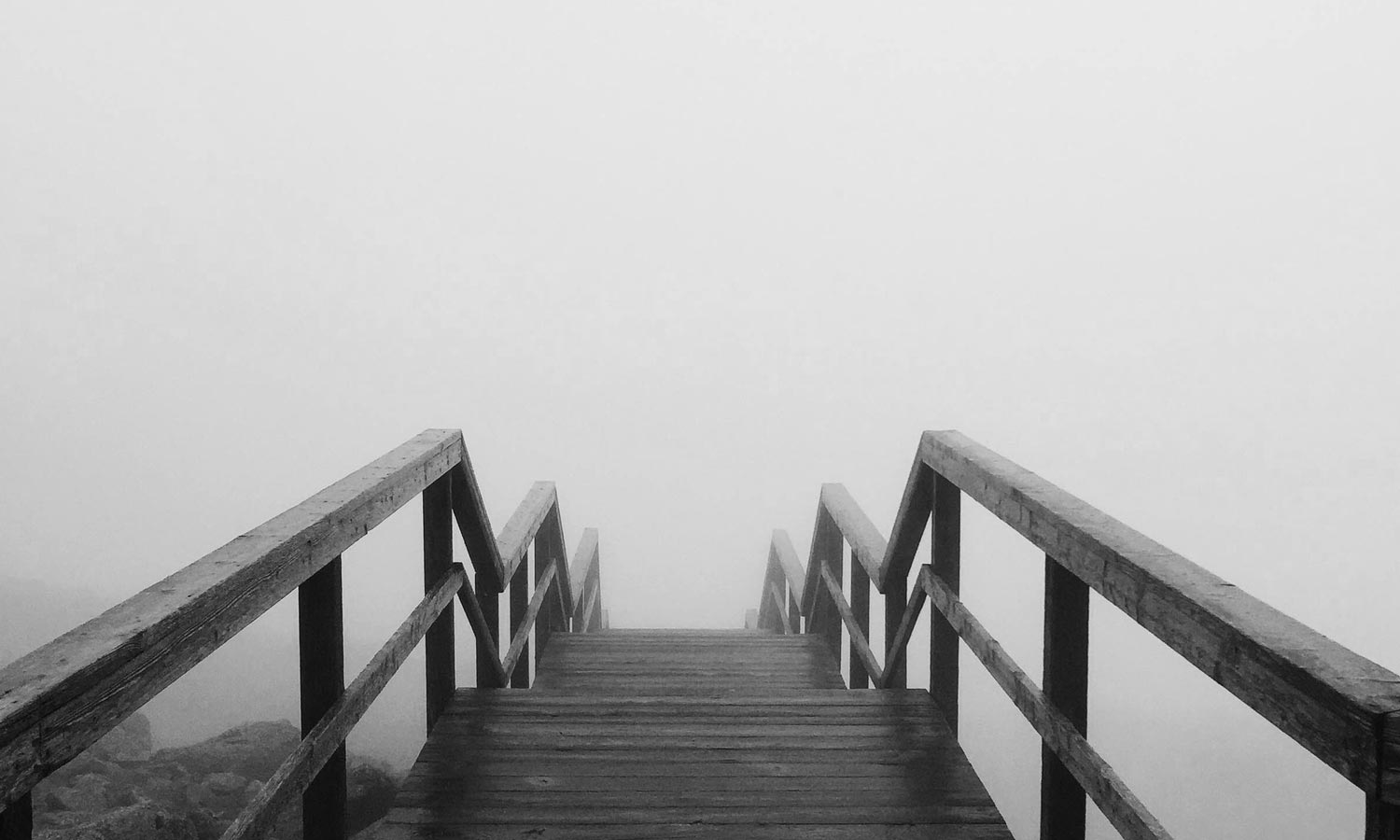 Atmospheric boardwalk disappearing into fog